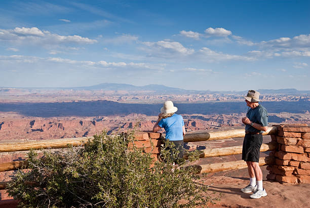 Viewing the Canyons Canyonlands National Park, Utah, USA - May 17, 2012: A senior couple are enjoying the view with the evening light and clouds from Grandview Overlook. jeff goulden canyonlands national park stock pictures, royalty-free photos & images