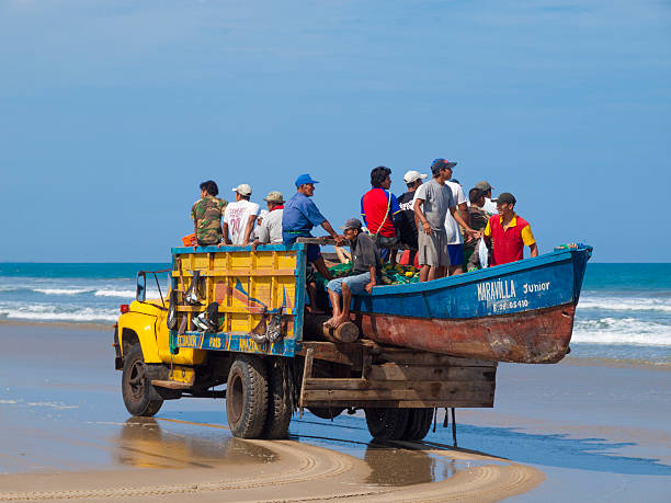 Montanita, Ecuador "Montanita, Ecuador - July 10, 2009: Small Beach town of Montanita on the coast of Ecuador. A truck loaded with people and a boat hanging out the back drives on the beach. People can also be seen in the background. On close inspection nets full of fish can be seen hanging from the truck." montanita ecuador stock pictures, royalty-free photos & images