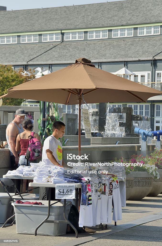Seattle Street Scene "Seattle, USA - September 8, 2011: A t-shirt vendor at the Seattle waterfront with people and Seattle Aquarium in the background." Selling Stock Photo