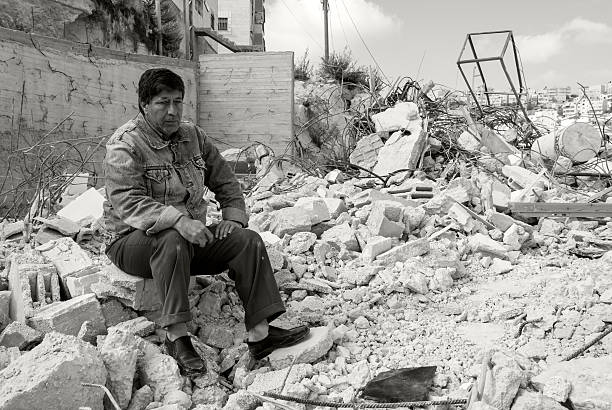 Anata, West Bank, Palestinian Territories - December 11, 2006: A Palestinian man sits outside his home on the outskirts of Jerusalem, demolished hours earlier by Israeli authorities. Building permits are often difficult for Palestinians to obtain in and around Jerusalem, forcing many to build illegally in order to house their families. In the past ten years, authorities have demolished more than 2,200 Palestinian residences.