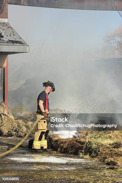 Firefighter Extinguishes Burning Hay Stock Photo - Download Image Now - Accidents and Disasters, Activity, Adult