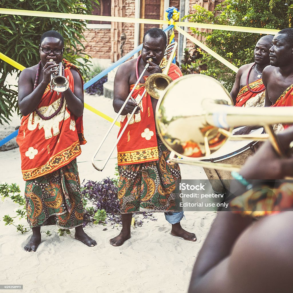 African musicians. "Ouidah, Benin - September 1, 2012: Small orchestra in traditional african dresses playing drums and horns at small traditional village party. This event was a free performance for people who live in neighborhood." Activity Stock Photo