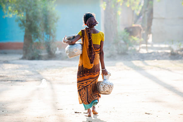 Bengali woman carrying water jar in village stock photo