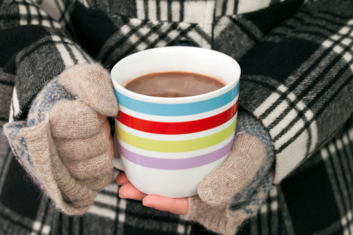 Gloved female hand holding a cup of hot chocolate.