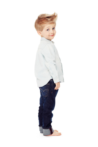 Side view of a cute little boy standing against a white background - portrait