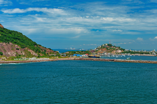 This great view is enjoyed entering Mazatlan with the city in the background the many boats and other buildings and the seawall in the midground.