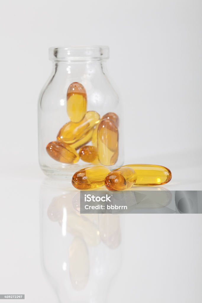 Jaune pilules de vitamines et un pot sur blanc - Photo de Bouteille libre de droits