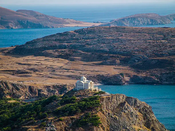 greek orthodox church build on top of a hill. panoramic view over the ocean and some islands
