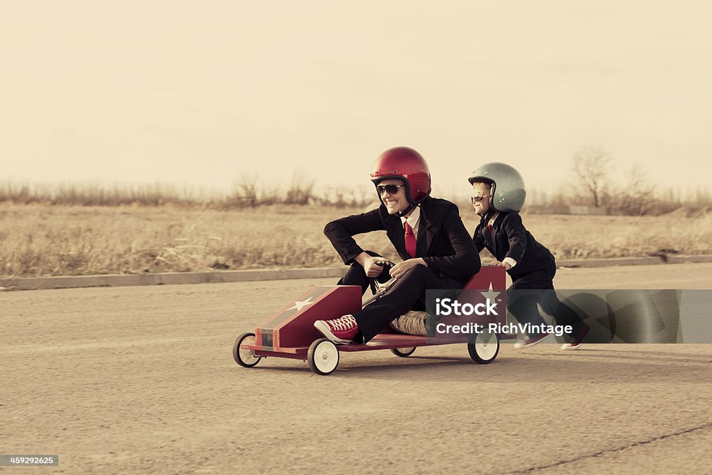 Young Business Boy Pushes Woman in Toy Car A young business team is ready for new adventures full of speed and accomplishment. Child Stock Photo