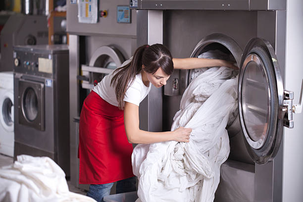 Laundry service. Female worker in laundry service,get washed sheets out of washing machine Laundry Service stock pictures, royalty-free photos & images