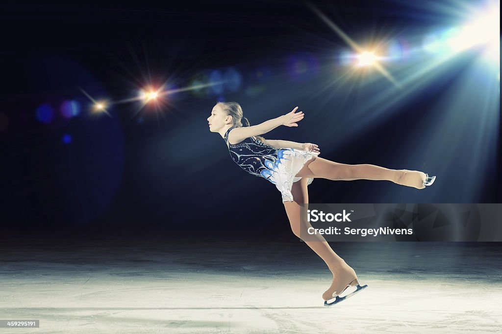 Young girl figure skating with spotlight on her Little girl figure skating at sports arena Figure Skating Stock Photo