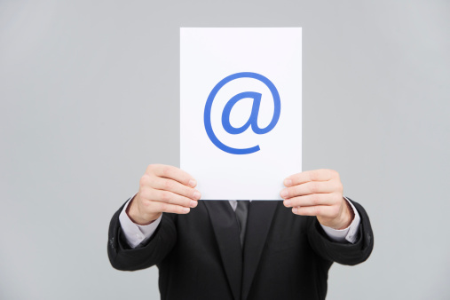 Businessman is holding a at sign, isolated on gray background