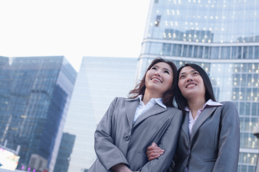 Portrait of smiling businesswomen linking arms, outdoors, Beijing