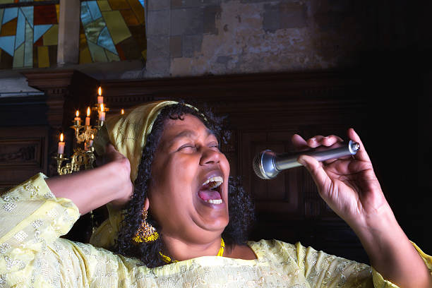 Singing for the Lord Closeup of a mature gospel or soul singer in a dark church black female gospel singers stock pictures, royalty-free photos & images