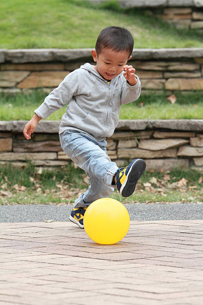 Japanese boy kicking a yellow ball (3 years old)