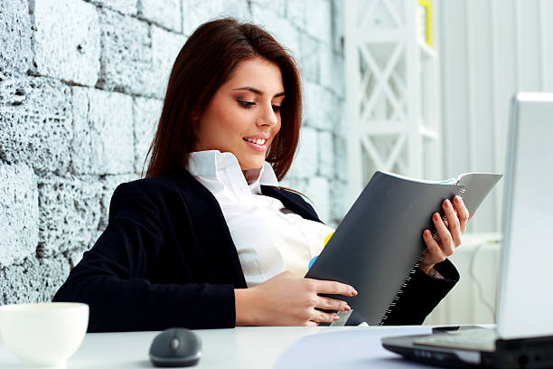 istock Young beautiful happy businesswoman reading the notebook 459331301