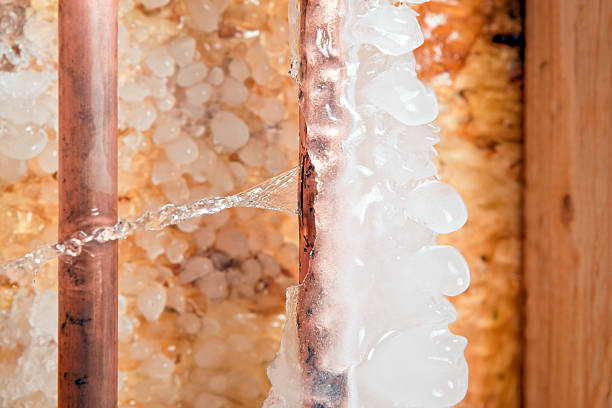 Frozen Ice Covered Cracked Copper Water Pipe Leaking A household 1/2" copper water pipe has frozen and cracked. The left pipe is hot water the right cold. Water is leaking from the crack into an unfinished basement area, the background is oriented strand board (OSB) and ice. This type of crack can happen in cold areas with poor insulation. The water inside the pipe freezes causing the crack, once water starts to flow a large amount of damage can quickly occur. frozen water stock pictures, royalty-free photos & images