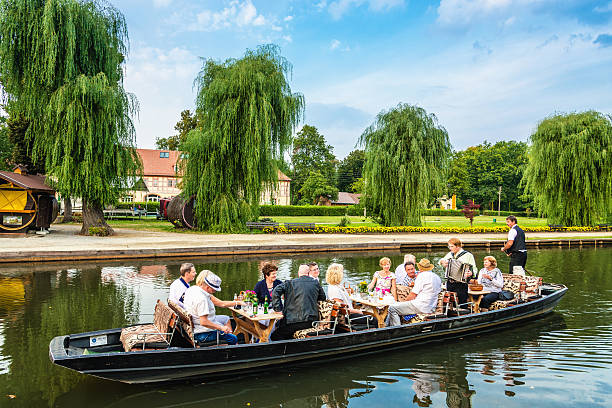 Celebrating on ark in the Spreewald (Lübbenau) Lübbenau, Germany - August 30, 2013: A group of people on a party river boat ride accompanied by accordion music through the Spreewald returning to Lübbenau harbour. Several hours lasting ark trips (german Kahnfahrt) through the over 200 small canals and waterways, forest and wetlands of the Spreewald, are a popular tourist attraction for nature lovers, day tripers as well as groups on guided party tours alike. spreewald stock pictures, royalty-free photos & images