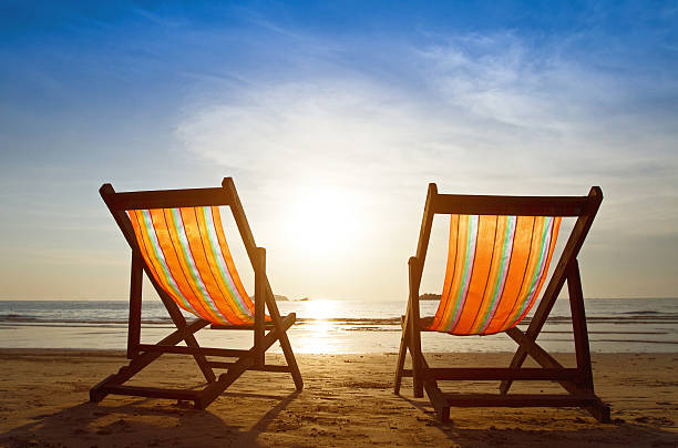 istock Two wooden deck chairs on the sand facing toward the sea 459361737