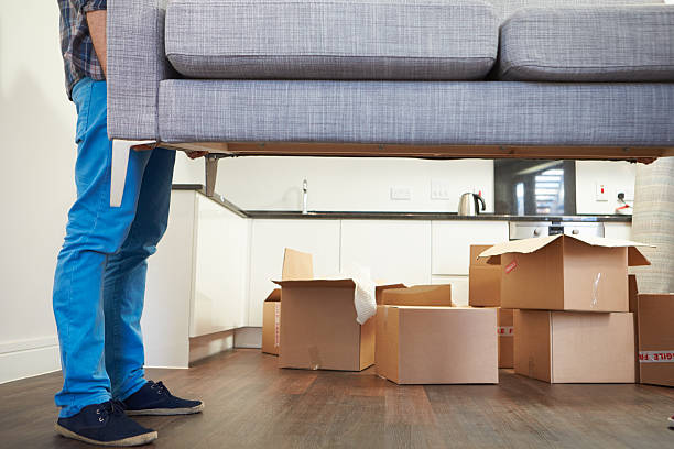 Man Carrying Sofa As He Moves Into New Home