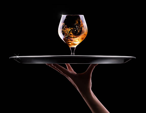 Cognac or brandy on a black waiter hand and tray with Cognac or brandy on a  black background cognac region photos stock pictures, royalty-free photos & images