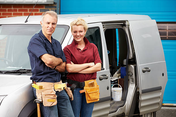 Workers In Family Business Standing Next To Van Workers In Family Business Standing Next To Van Smiling At Camera woman wearing tool belt stock pictures, royalty-free photos & images