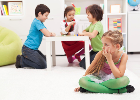 Little girl sitting lonely - feeling excluded by the others