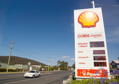 Mittagong, Australia - December 18, 2013: A car drives past a Shell service station price board displaying high petrol prices on the Old Hume Highway.