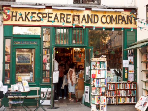 Paris, France - September 25, 2011: Outdoor view of Shakespeare and Company bookstore in Paris, France, while people have a look at books inside. Shakespeare and Co. is an independent bookstore located in the 5th arrondissement and is a famous landmark for lovers of English literature in Paris.