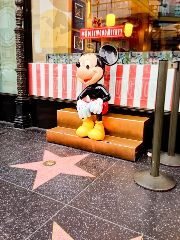 Hollywood, USA - May 7, 2013: Mickey Mouse sitting on a bench on Hollywood Boulevard, Hollywood Hall of fame, Star of Donald Duck is closest to Mickey.