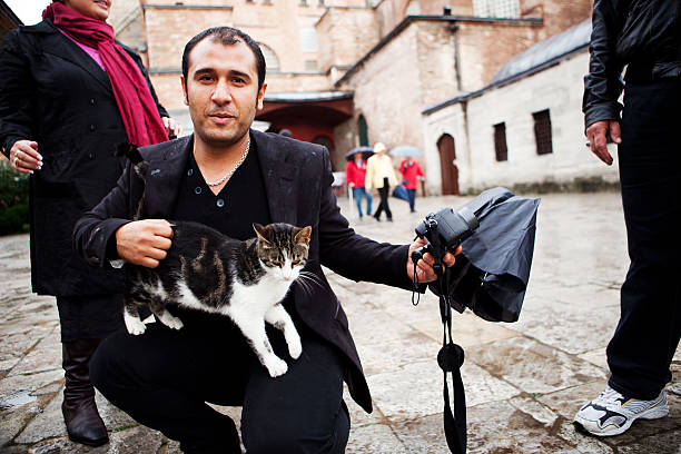 Istanbul, Turkey - November 4, 2009: A man takes a moment to pet a cat from the street in Istanbul.