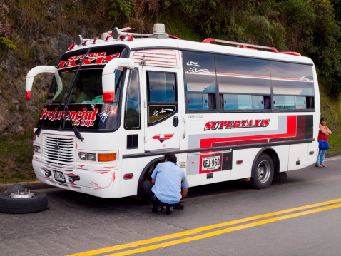 Ipailes, Colombia - June 23, 2009: Broken down bus by the side of the road near Ipailes in Colombia - passenger stands by the side of the bus while the driver attempts to re-attach a wheel that has fallen off.