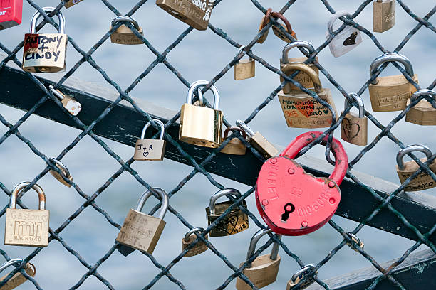 Paris, France - May 14, 2011: Close up of locks tied on the fence of the Pont des Arts. Among the locks is one large heart shaped red lock.
