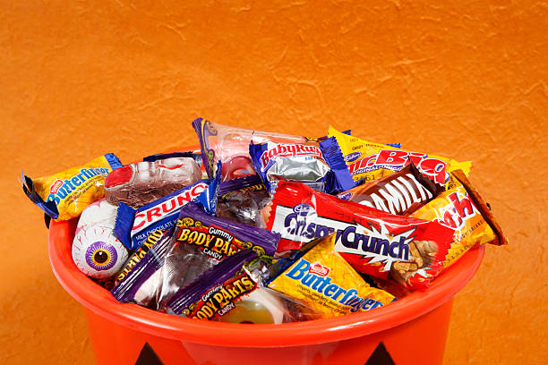 Bucket of Halloween Candies Cantley, Quebec, Canada - October 3, 2011: A product shot of an assortment of different halloween candies with Mr Big (Cadbury), Crispy Crunch (Cadbury), Caramilk (Cadbury), Crunchie (Cadbury), Butterfinger (Nestle), Baby Ruth (Nestle), Crunch (Nestle), Gummy Body Parts (Frankford), Dr. Scab\\\'s Monster Lab (Balmer) in a pumkin. All is on a orange background. cadbury plc photos stock pictures, royalty-free photos & images