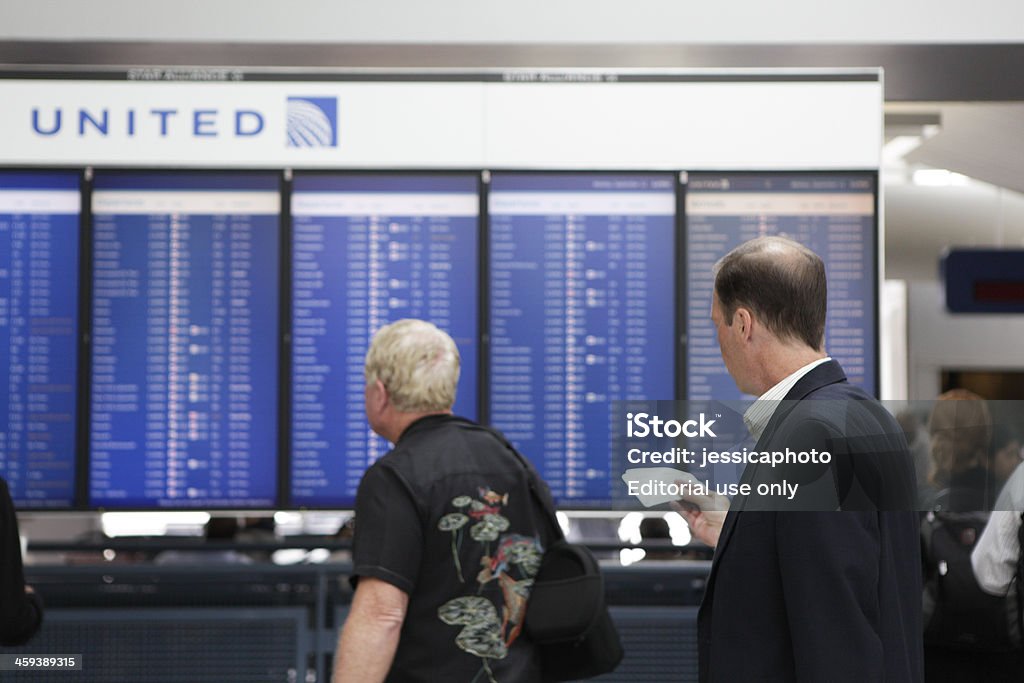 Departures Board Chicago, Illinois, USA - September 12, 2011: Men at Chicago's O'Hare International Airport read departures list for United Airlines. O'Hare is one of the busiest airports in the world. United Airlines Stock Photo