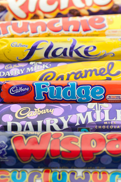 Cadbury Chocolate Bars Weybridge, England-October 1, 2011: Row of different Cadbury Chocolate Bars.  Focus is on the Fudge bar.  Cadbury is a candy company based in London, England and distributed by Kraft.  The bars in this picture include Curlywurly, Wispa, Fudge, Dairy Milk Chocolate, Caramel, Flake, Crunchy and Picnic. cadbury plc photos stock pictures, royalty-free photos & images