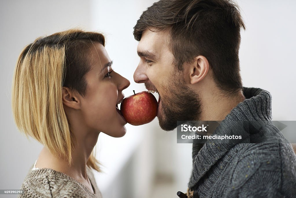 Couple with healthy teeth Charming young couple biting one apple Apple - Fruit Stock Photo