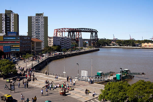 Buenos Aires, Argentina - March 27, 2011: La Boca neighborhood, Riachuelo view. People walking along the malecAn. In the background,Roca Bridge.