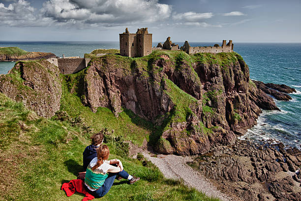 Stonehaven, Scotland, United Kingdom - August 20, 2011: young couple near the rocky cliffs of Dunnottar Castle, located just outside Stonehaven in Aberdeenshire, Scotland