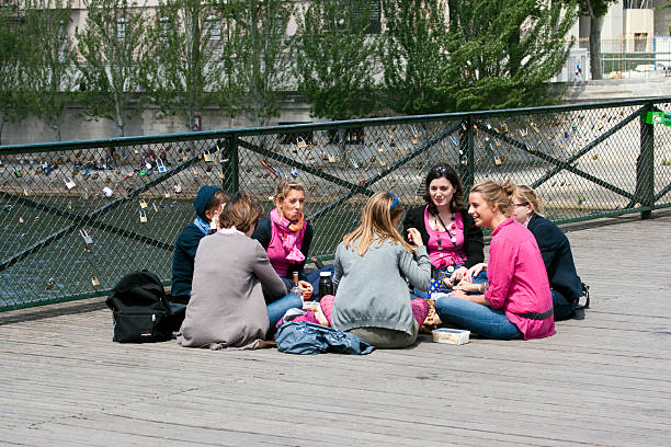 Paris, France - May 14, 2011: Group of young women sitting in a circle on the Pont des Arts in Paris. Eating, talking and drinking.