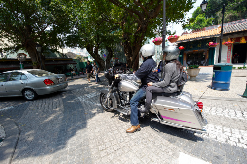 Macau, Macau S.A.R. - April 3, 2011: a chinese couple riding an Harley-Davisdon motorbike in Rua Governador Tamagnini Barbosa. Taipa Village.