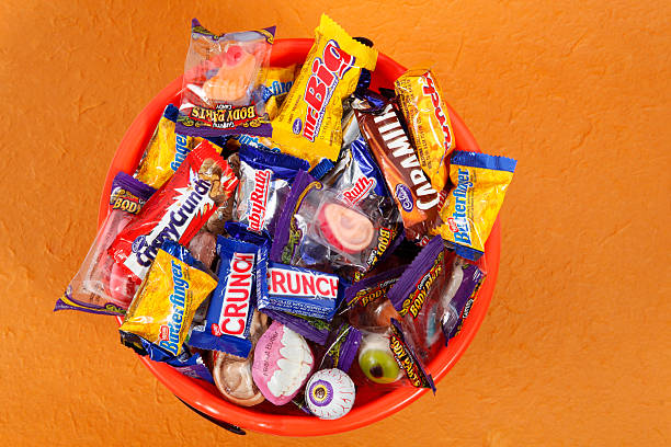Bucket of Halloween Candies Cantley, Quebec, Canada - october 3, 2011: A product shot of an assortment of different halloween candies with Mr Big (Cadbury), Crispy Crunch (Cadbury), Caramilk (Cadbury), Crunchie(Cadbury), Butterfinger (Nestle), Baby Ruth (Nestle), Crunch (Nestle), Gummy Body Parts (Frankford), Dr. Scab\'s Monster Lab (Balmer)  in a pumkin. All is on a orange background. cadbury plc photos stock pictures, royalty-free photos & images