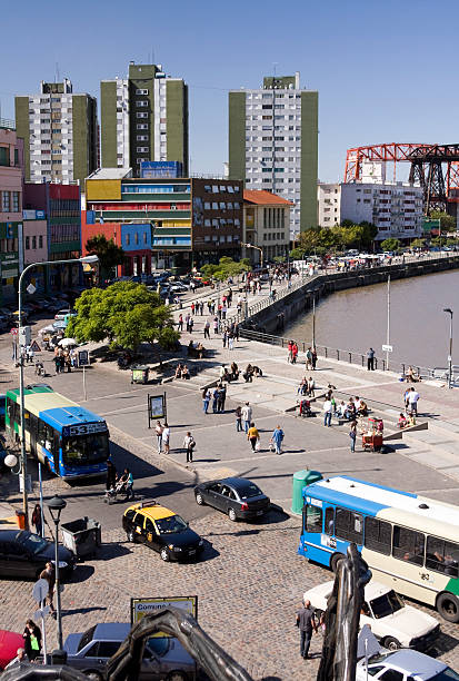 Buenos Aires, Argentina - March 27, 2011: La Boca neighborhood, Riachuelo view. People walking along the malecAn. In the background, Roca Bridge.
