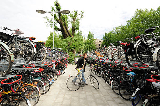 a teenager boy of European appearance with short blond hair in a T-shirt stands with a bicycle in the park.looks at the camera on the left there is a place for an inscription. High quality photo