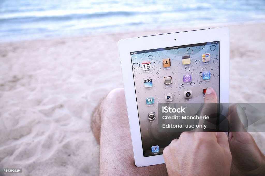 Homem tocando iPad2 tela inicial na praia - Foto de stock de .com royalty-free