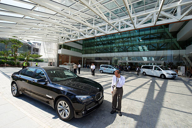Singapore, Singapore - May 02, 2010: a male singaporean driver talk on the cellphone while waiting for the passenger to arrive, at the entrance of Marina Bay Sands Hotel. The man is standing beside the Bmw car he drive.