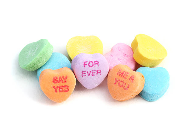West Palm Beach, USA - January 23, 2012: This is a closeup studio shot of a pile of Sweethearts Candies. These candies are heart shaped pieces inscribed with romantic or flirtatious phrases. The visible phrases in this image are For Ever, Say Yes, and Me and You.  Sweethearts Candies are made by the New England Confectionary Company.