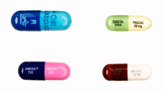 Truro, MA USA - October 20, 2011: Four pills on white: Prozac, 20 mg, Amoxicillin 250 mg, Cardizem 180 mg and Bristol 7278 wich is a drug called Trimox 250 mg. Prozac is manufactured by Eli Lilly and Company.  Cardizem Biovail is manufactured by Pharmaceuticals, Inc. Amoxicillin is manufactured by Glaxo Smith Kline and Trimox 250 mg is  manufactured by bristol-myers squibb.