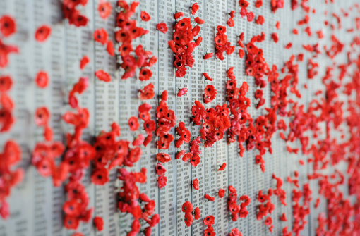 War Memorial, Canberra, Australia - December 23, 2011: Wall of names of those lost in war with poppy flowers placed by those showing their respects.