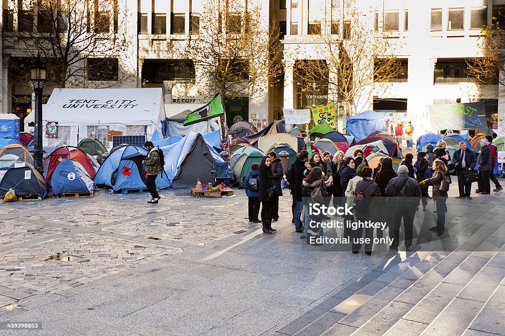 Occupy London Stock Exchange London, United Kingdom - December 2, 2011: Tents representing the movement " Occupy London Stock Exchange " protesting against the governament and the financial system outside St Paul's Cathedral, London, UK. Movement born from "Occupy Wall Street" in New York. Tourist on the foreground waiting to get into St Paul's Cathedral. Activist Stock Photo